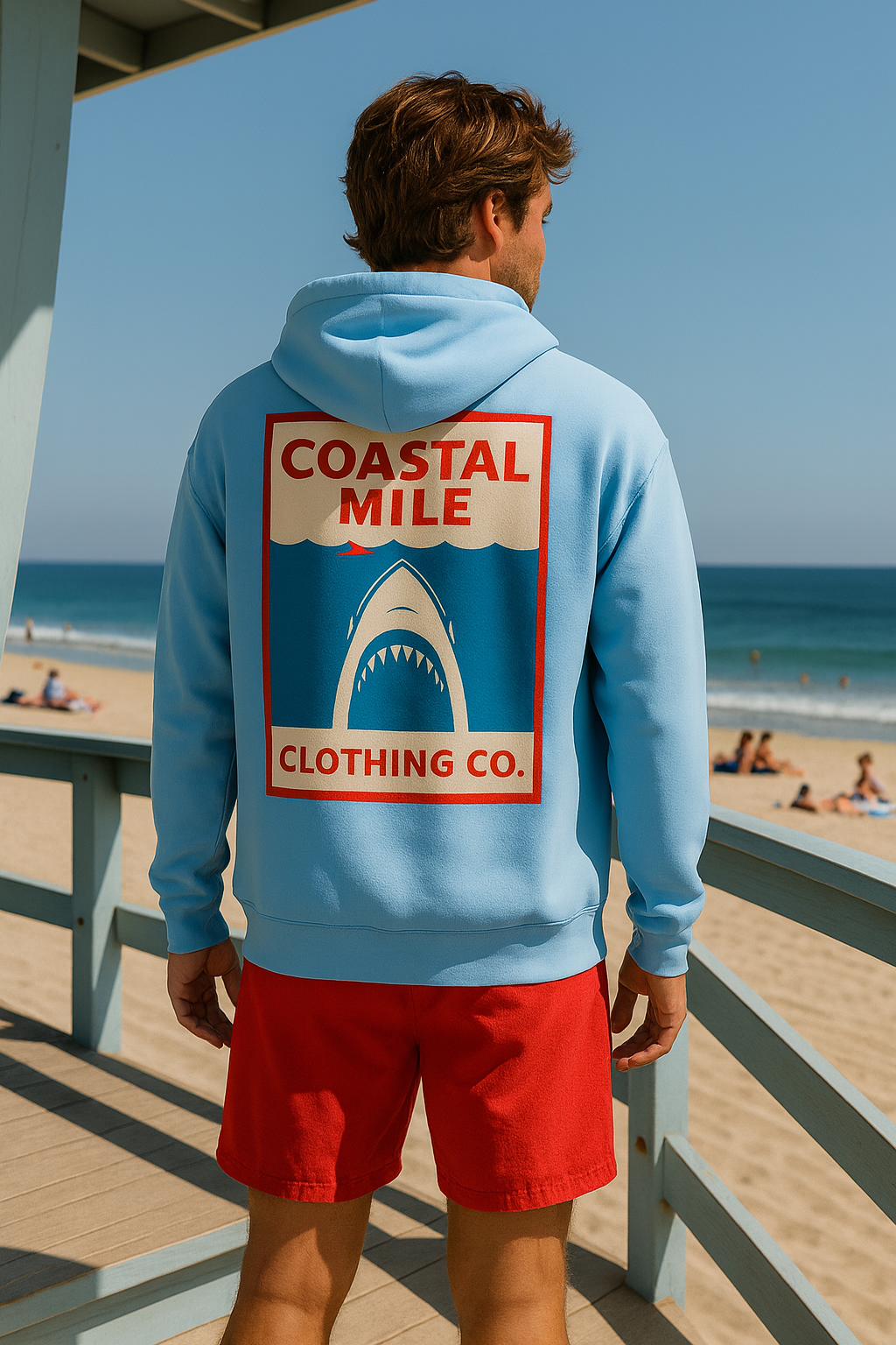 Person wearing a blue hoodie with 'Coastal Mile Clothing Co.' logo at the beach